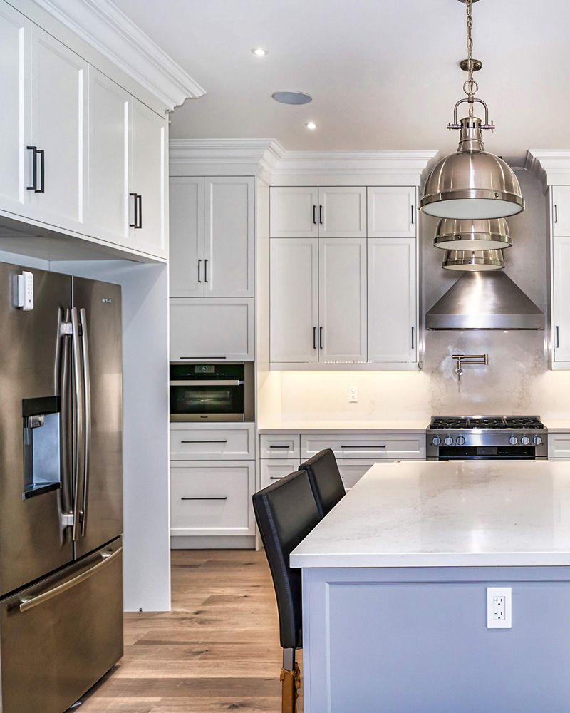 A kitchen with stainless steel appliances and white cabinets in Hazelridge Dr by Oakroots Construction