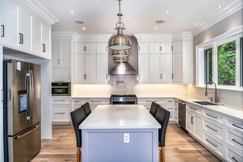 A kitchen with white cabinets, stainless steel appliances, and a large island in Hazelridge Dr by Oakroots Construction