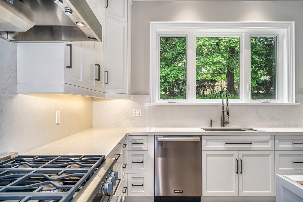 A kitchen with white cabinets and stainless steel appliances in Hazelridge Dr by Oakroots Construction