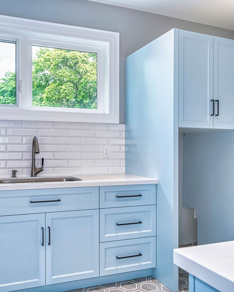 A kitchen with blue cabinets and white countertops in Hazelridge Dr by Oakroots Construction