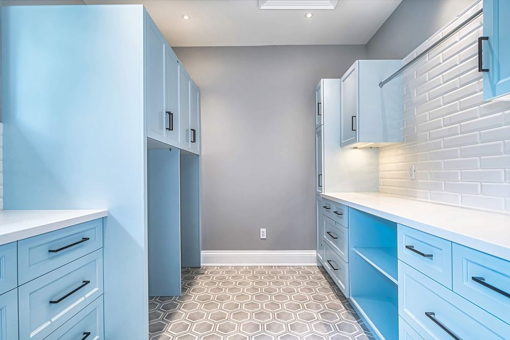 A kitchen with blue cabinets and white countertops in Hazelridge Dr by Oakroots Construction