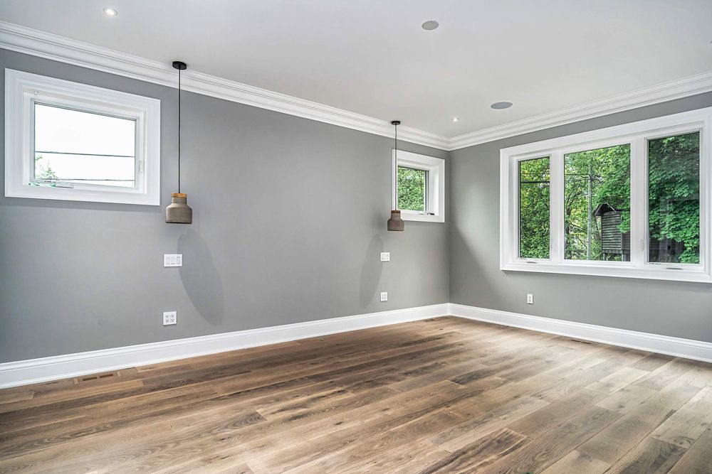 An empty room with hardwood floors, gray walls and white trim in Hazelridge Dr by Oakroots Construction