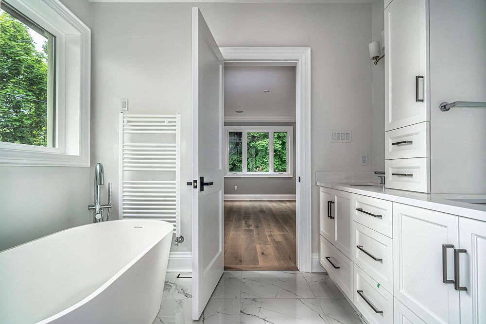 A bathroom with a tub, cabinets, drawers and a window in Hazelridge Dr by Oakroots Construction
