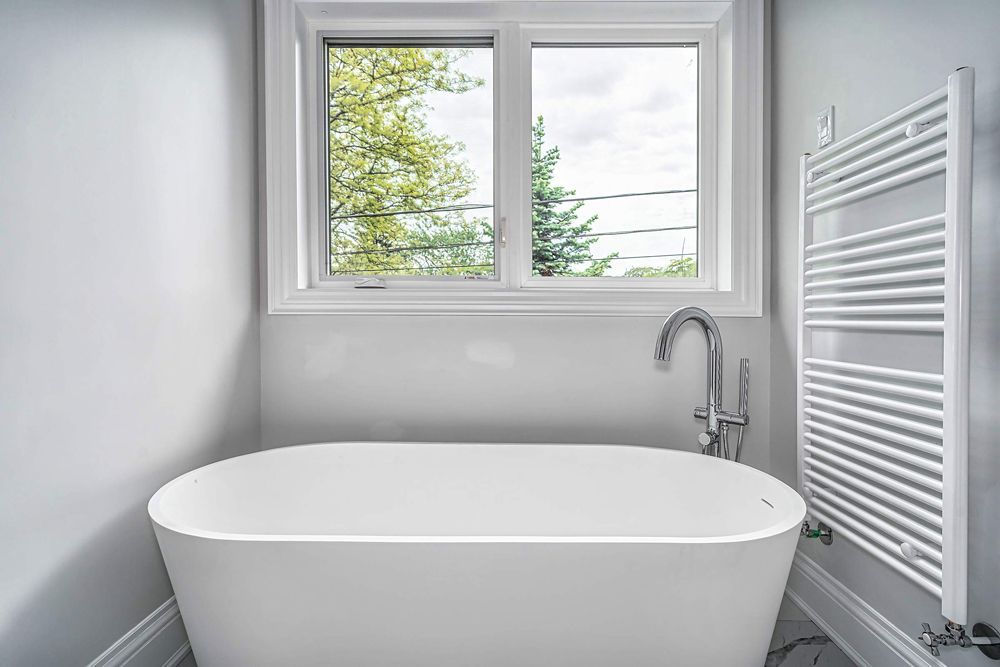 There is a bathtub in the bathroom next to a window in Hazelridge Dr by Oakroots Construction
