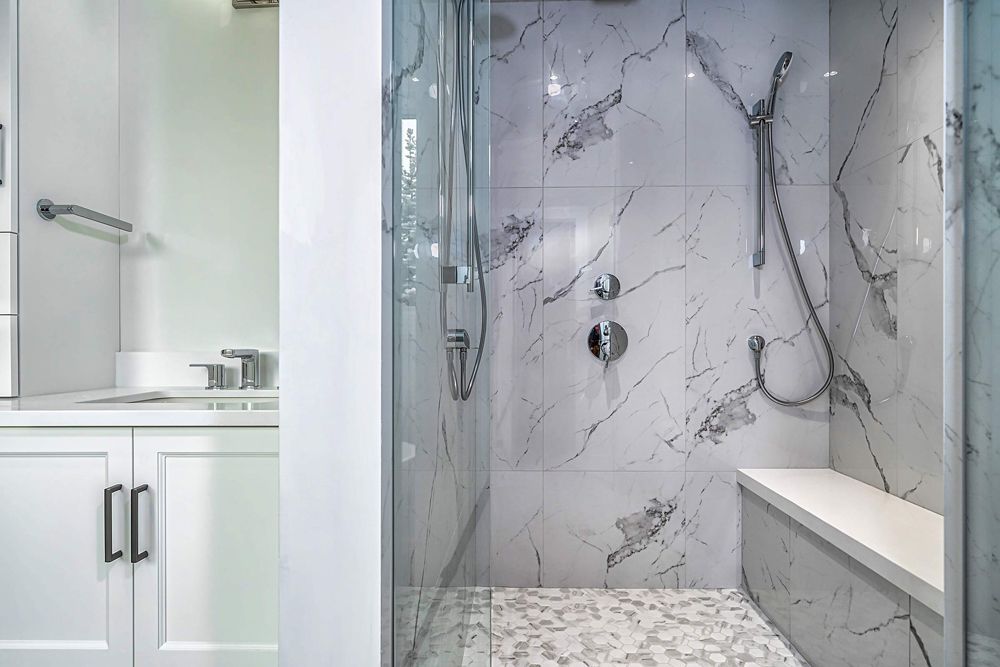 A bathroom with a walk-in shower and a bench in Hazelridge Dr by Oakroots Construction
