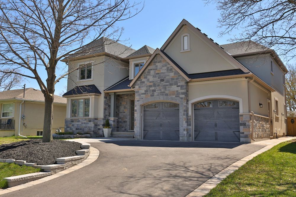 A large house with two garages and a tree in front of it