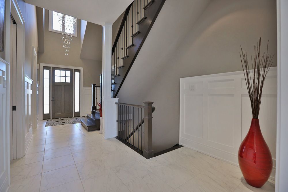 A large hallway with a staircase and a red vase
