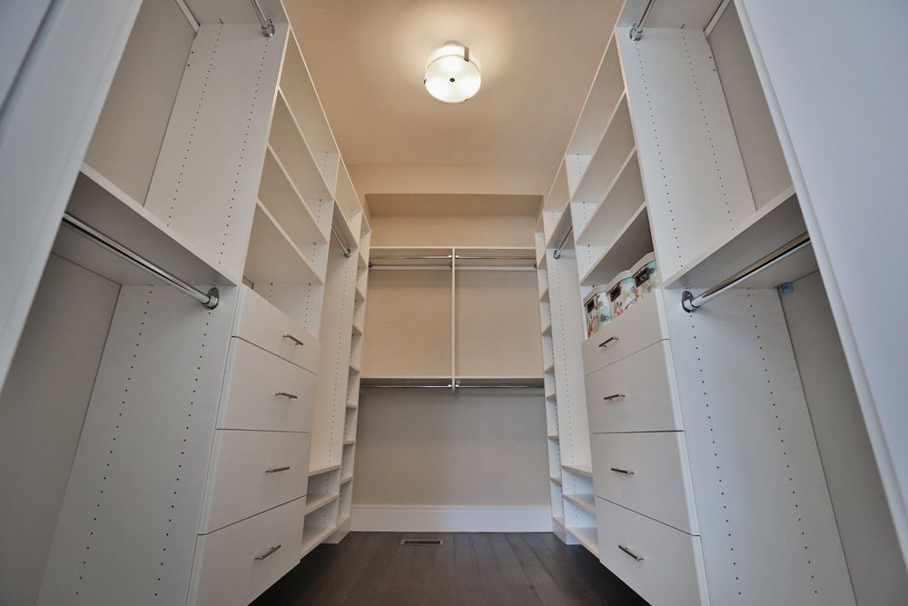 A walk in closet with lots of shelves and drawers