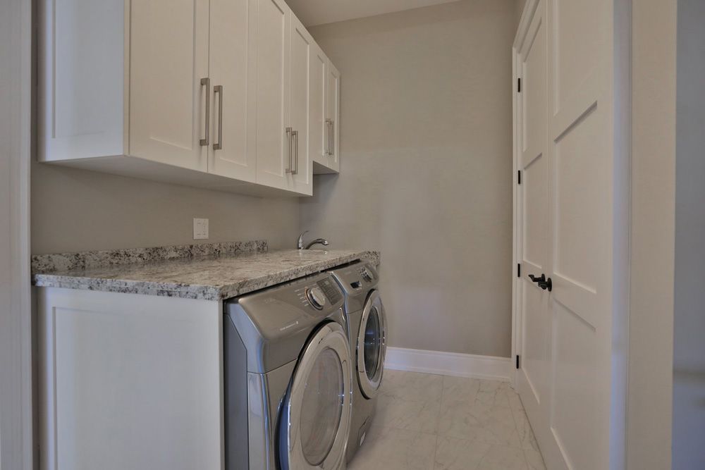 A laundry room with a washer and dryer and white cabinets.