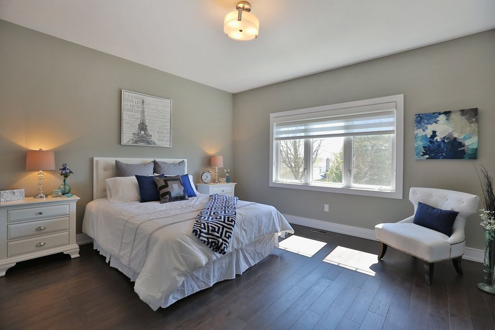 A bedroom with a bed , chair , nightstand and window.