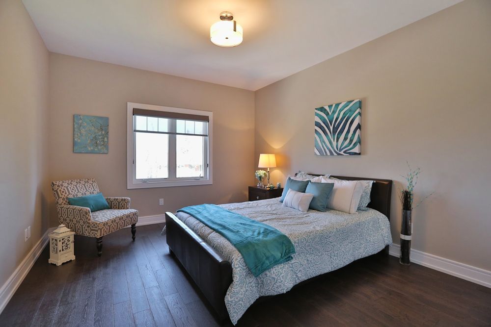 A bedroom with a bed , chair , nightstand and window.