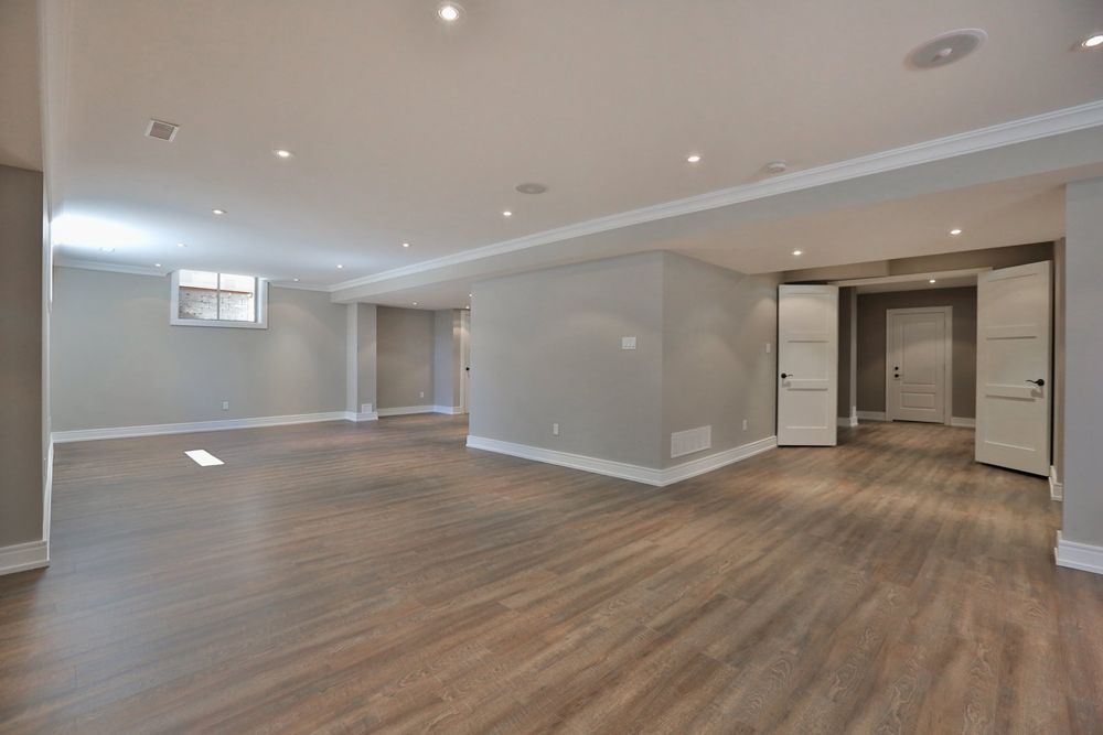 An empty basement with hardwood floors and gray walls.