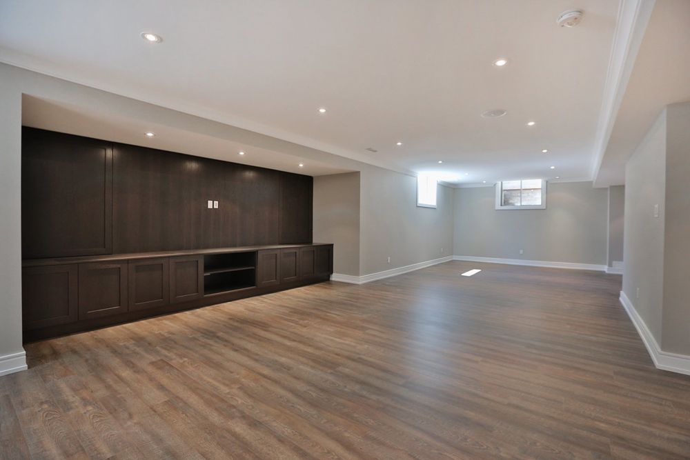 An empty basement with hardwood floors and cabinets.