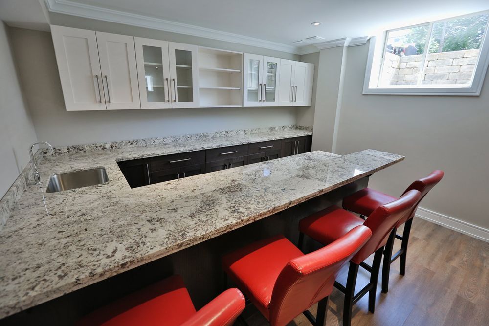 A kitchen with granite counter tops and red chairs