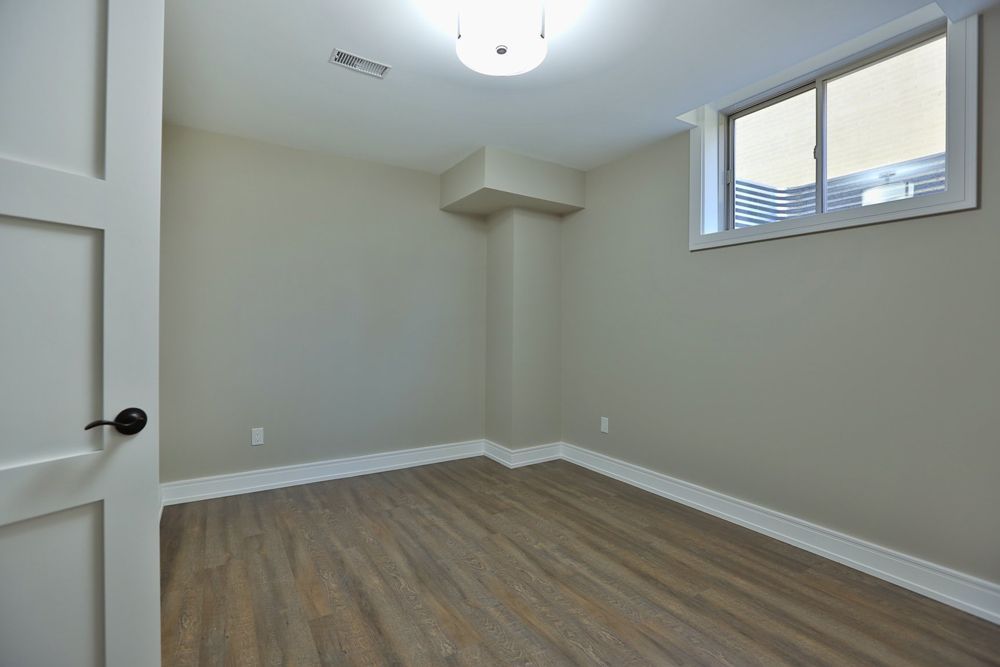 An empty room with hardwood floors and a window.