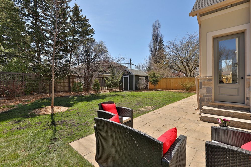 A patio with chairs and a couch in the backyard of a house.
