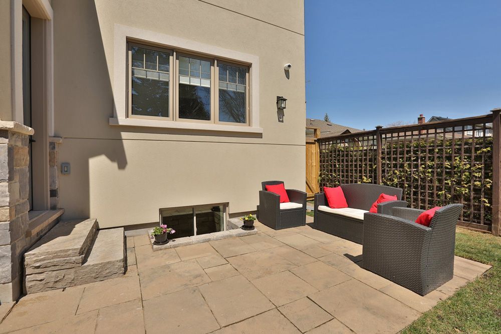 A patio with a couch and chairs in front of a house