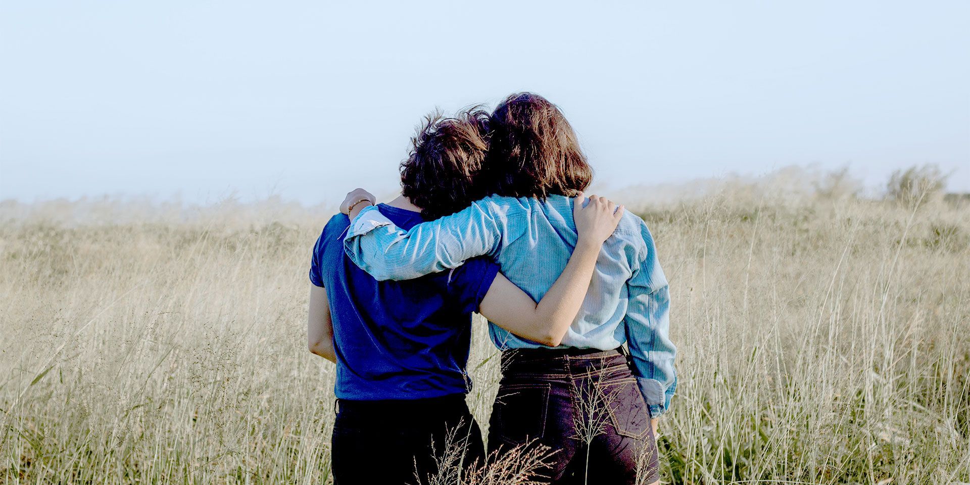 two women are hugging each other in a field of tall grass .