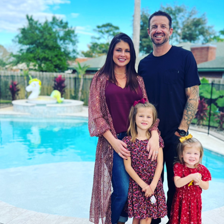 A family posing for a picture in front of a pool