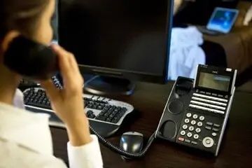 Woman Using a Desk Phone in An Office Setting — Pacific Telephone & Data In Cardiff, NSW