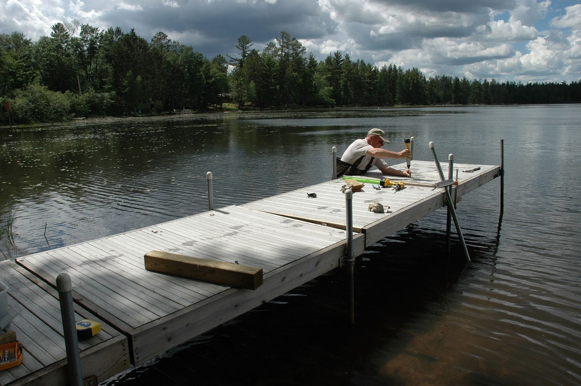 A man sits on a dock in the middle of a lake