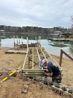 A group of men are building a dock on the shore of a lake.
