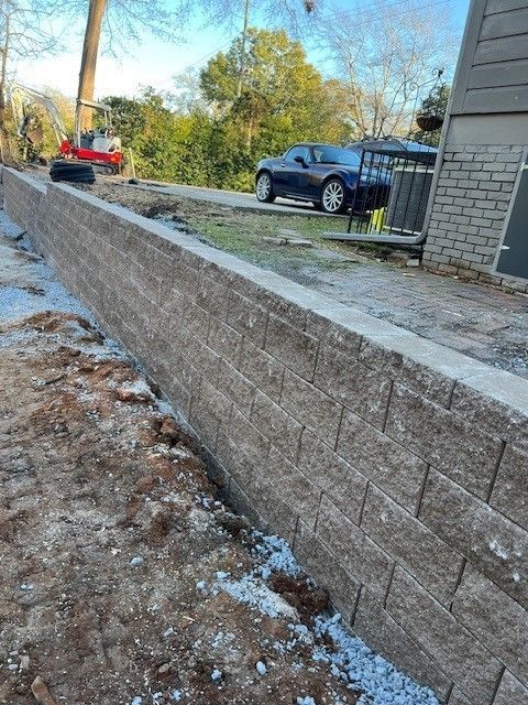 A stone wall along a river with trees in the background