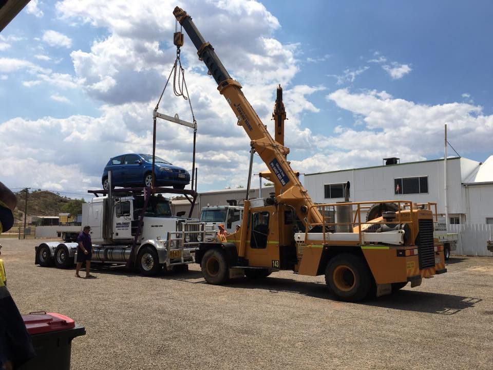 A Truck With A Blue Car On Top Of It Is Being Lifted By A Crane — Superior Machinery Maintenance In Ryan, QLD