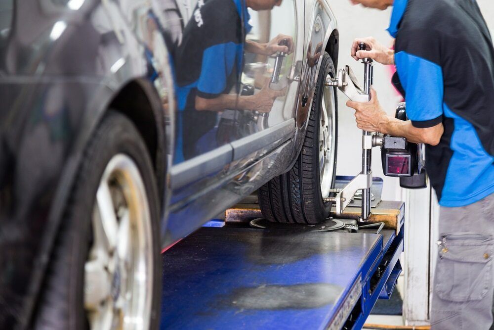 A Man Is Working On A Car On A Lift In A Garage — Superior Machinery Maintenance In Ryan, QLD