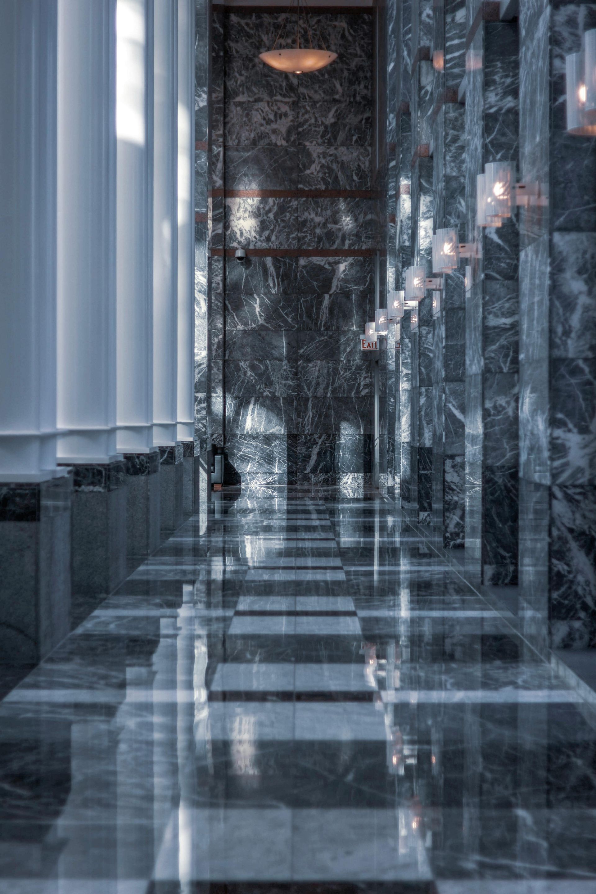 A long hallway with marble floors and columns in a building.
