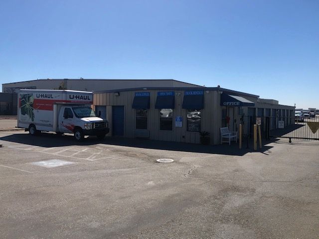 U-Haul truck parked near a storage facility office with blue awnings on a sunny day.