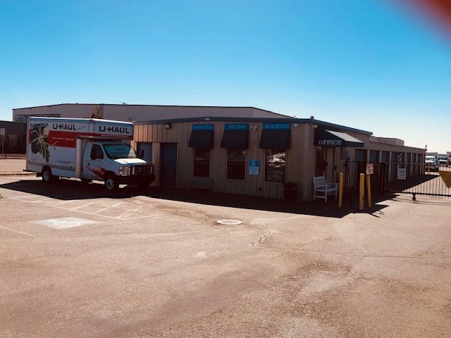 U-Haul truck parked outside a storage facility on a sunny day.