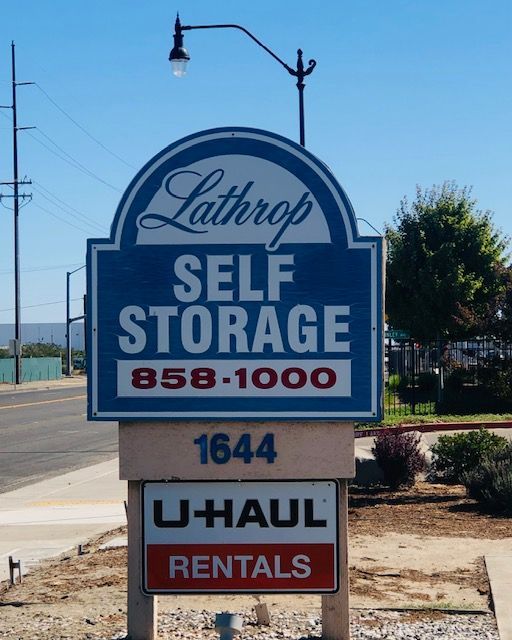 Sign for Lathrop Self Storage and U-Haul rentals, blue and white, with phone number and address.