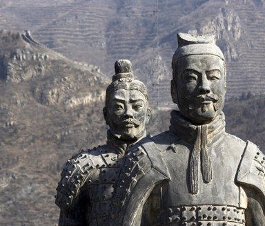 Statues of two Chinese warriors in stone; mountains in background.