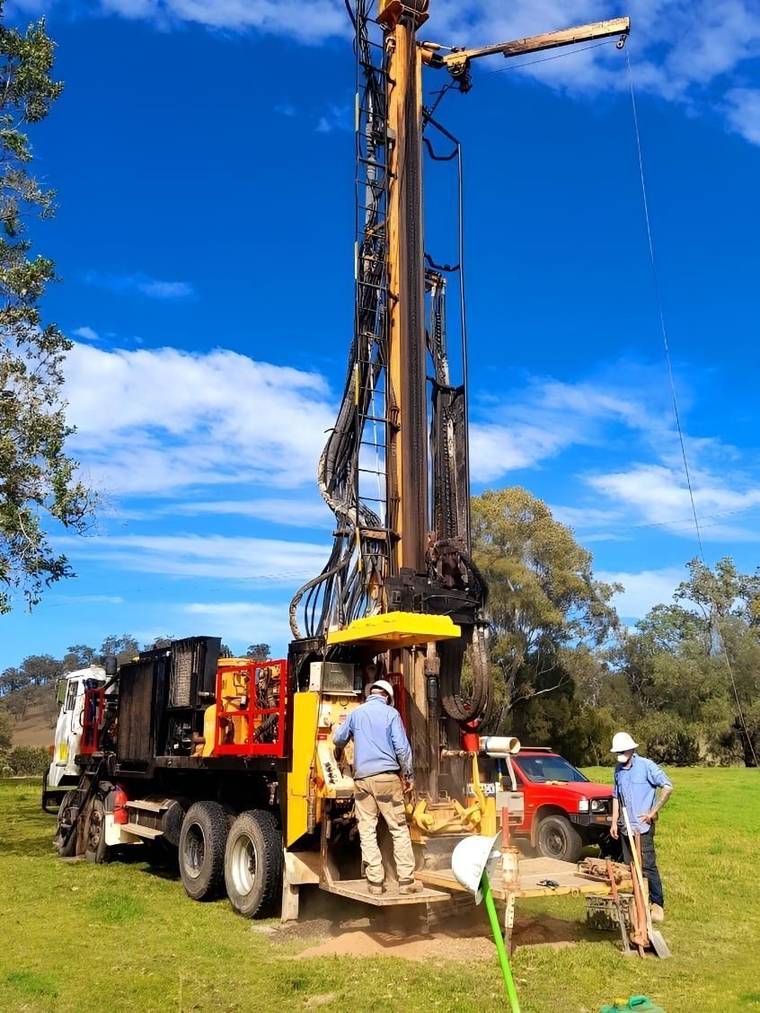 Drilling Rig With Workers in a Grassy Field — Local Drilling Services In South Burnett, QLD