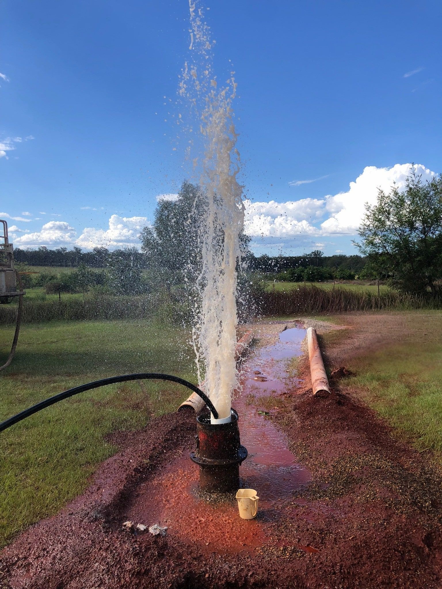 Well drilling with water gushing upwards into the sky — Local Drilling Services In Esk, QLD