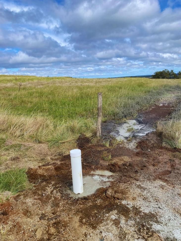 White Pipe in Muddy Ground, in a Grassy Field — Local Drilling Services In North Burnett, QLD