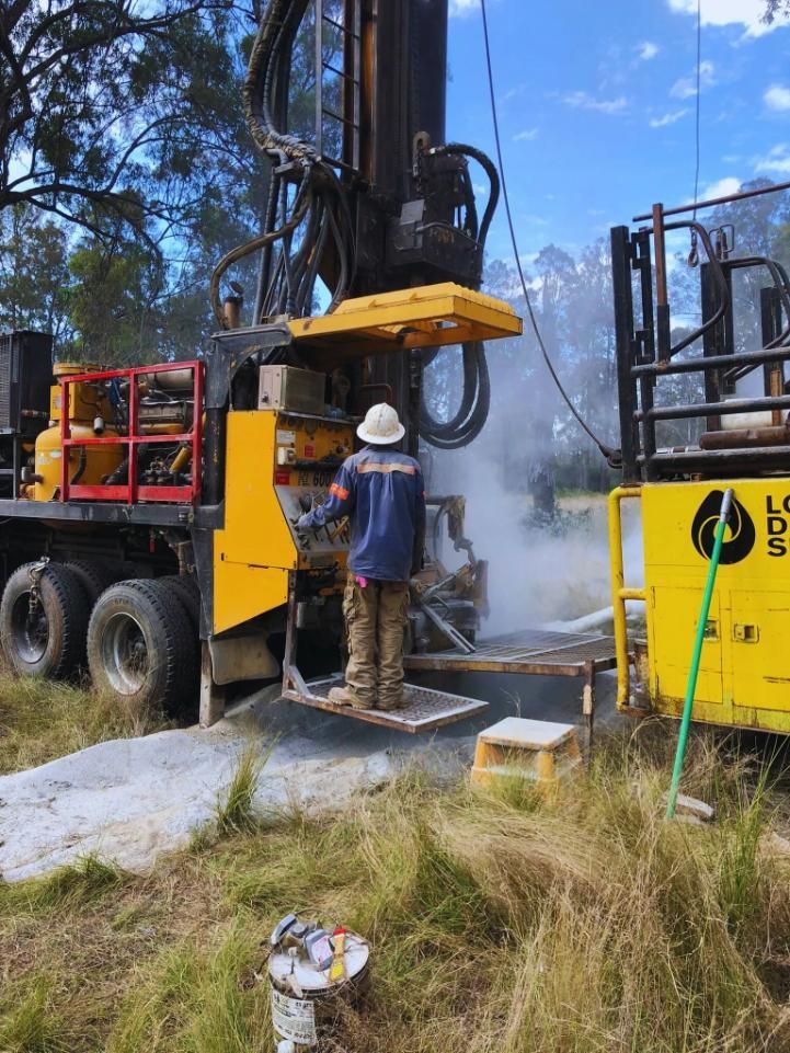 A Worker Operates a Yellow Drilling Rig in a Grassy Area — Local Drilling Services In Nanango, QLD