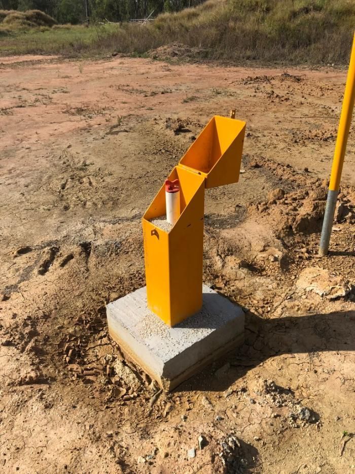 Yellow Metal Dispenser on Concrete Base in Dirt — Local Drilling Services In North Burnett, QLD
