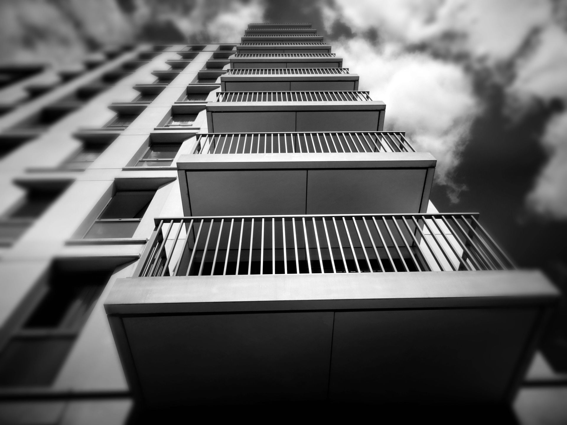 Symbolbild - Blick auf ein hohes Gebäude mit Balkonen vor einem bewölkten Himmel, denn wir machen Balkonen wieder fit