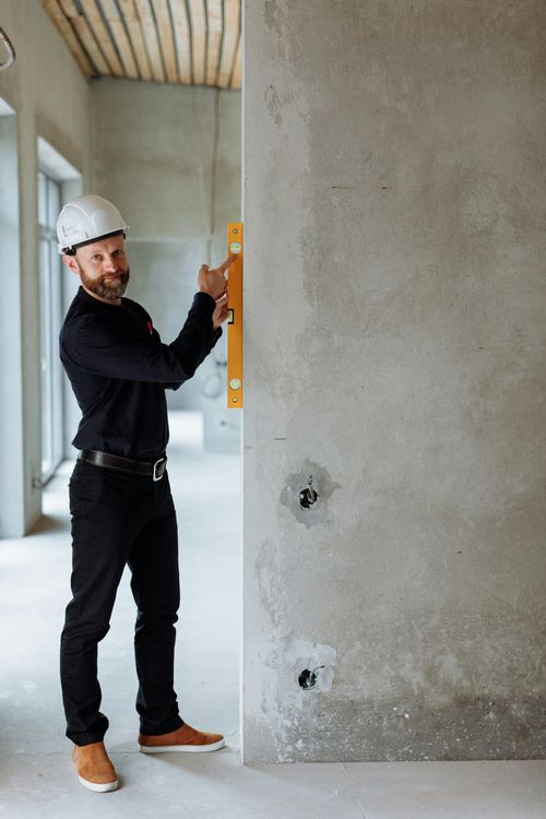 Symbolbild: Handwerker mit Wasserwaage – steht für Präzision und Qualität beim Bau