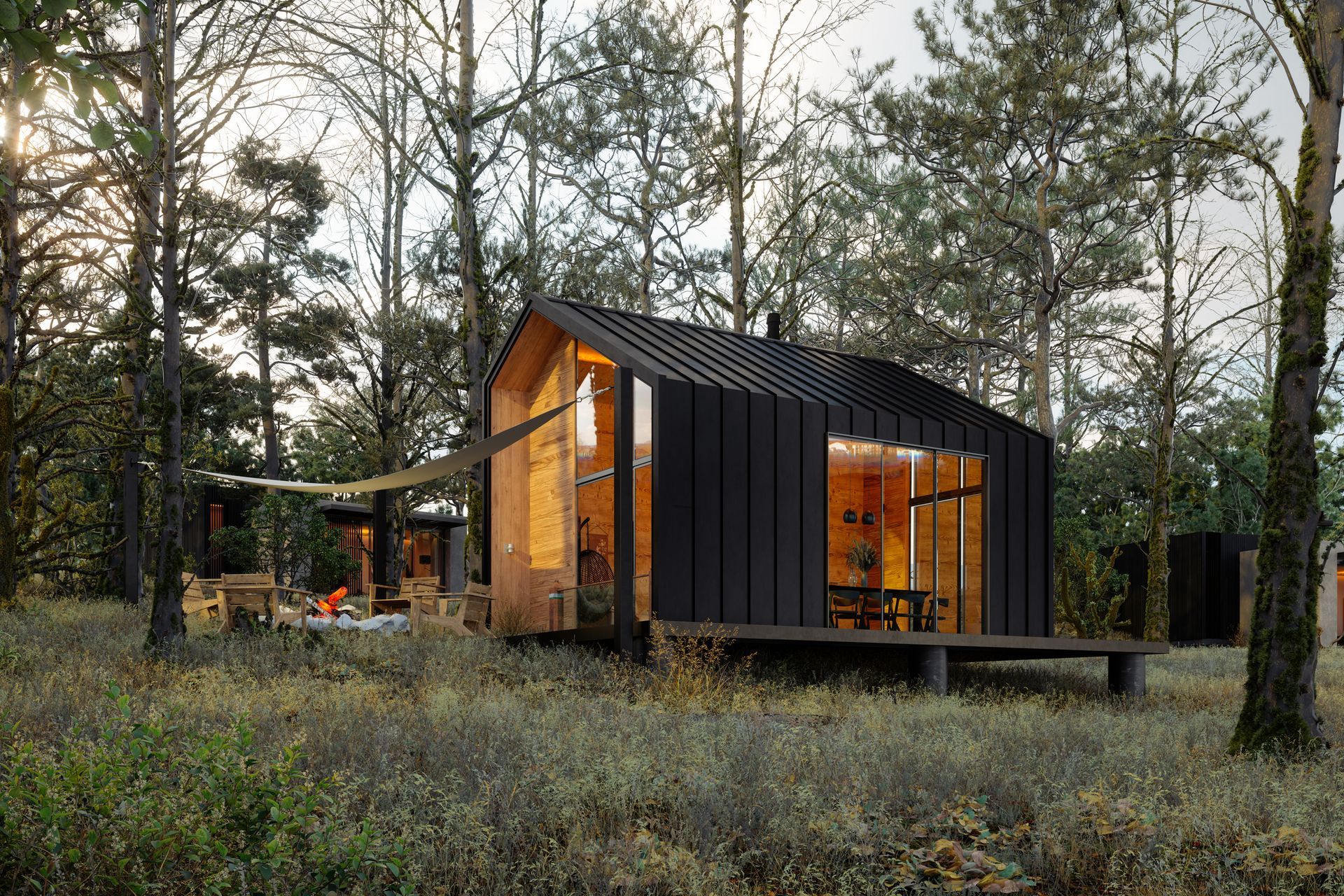 A small black house is sitting in the middle of a forest.