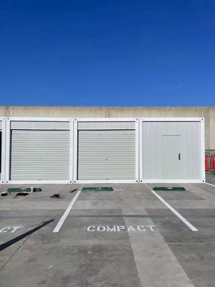 A wooden house with a glass door and windows is sitting in a warehouse.