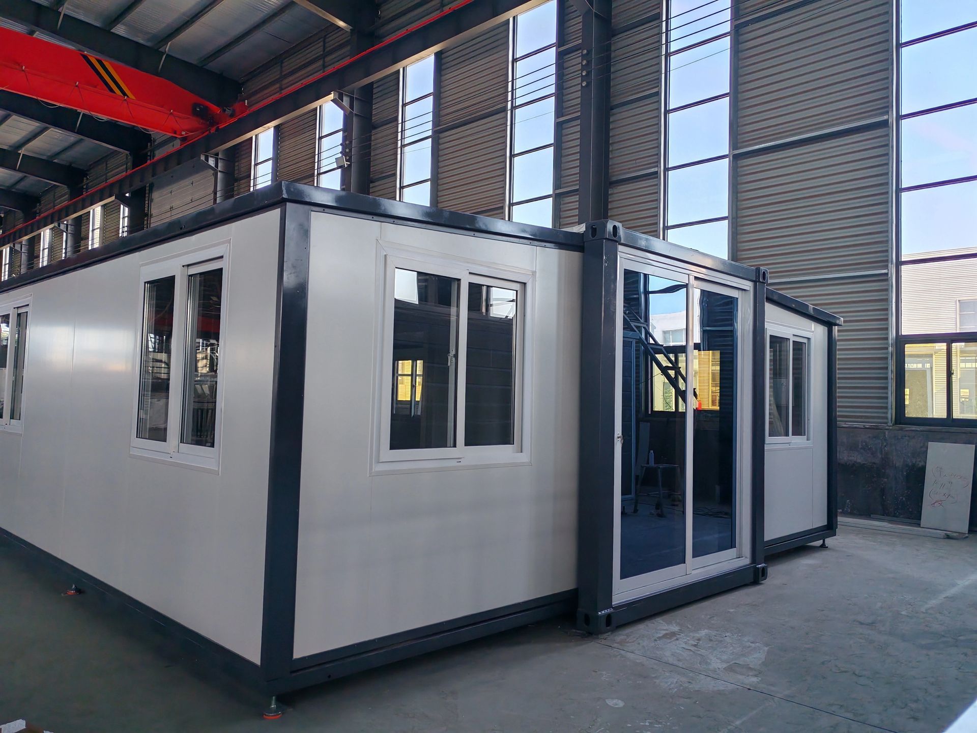 A large building with a lot of windows and doors is sitting in a warehouse.