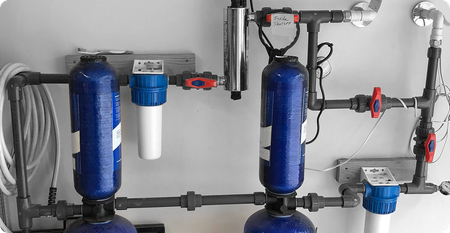 A water filter is hanging under a sink in a cabinet.