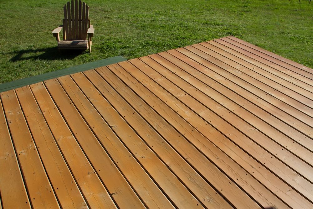 Wooden deck in a grassy yard with a chair in the background