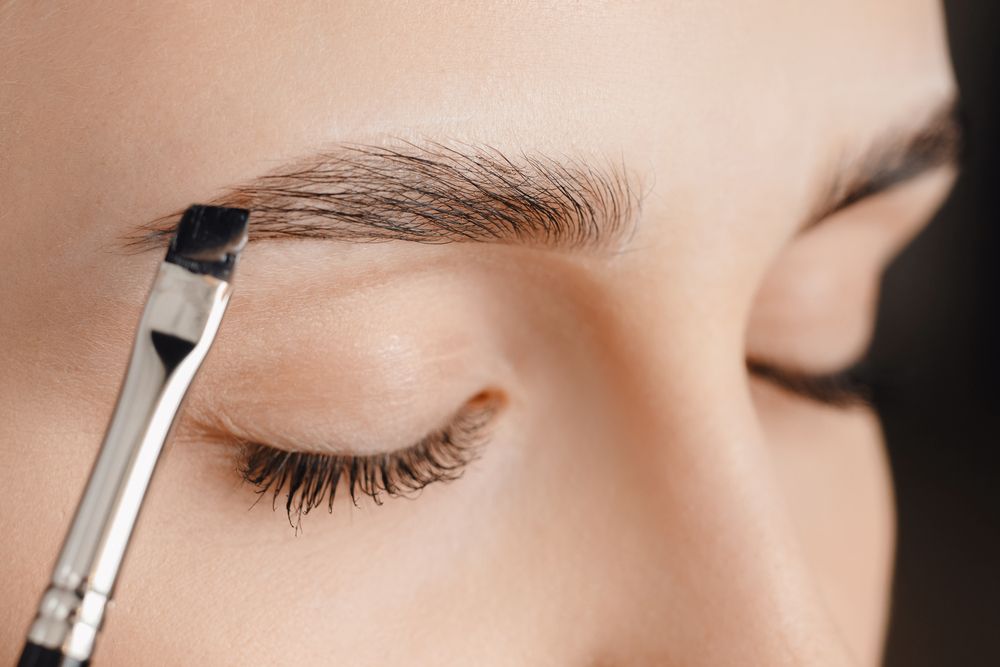 Person With Closed Eyes Applying Makeup — Oh So Blonde Hair Studio in Buddina, QLD
