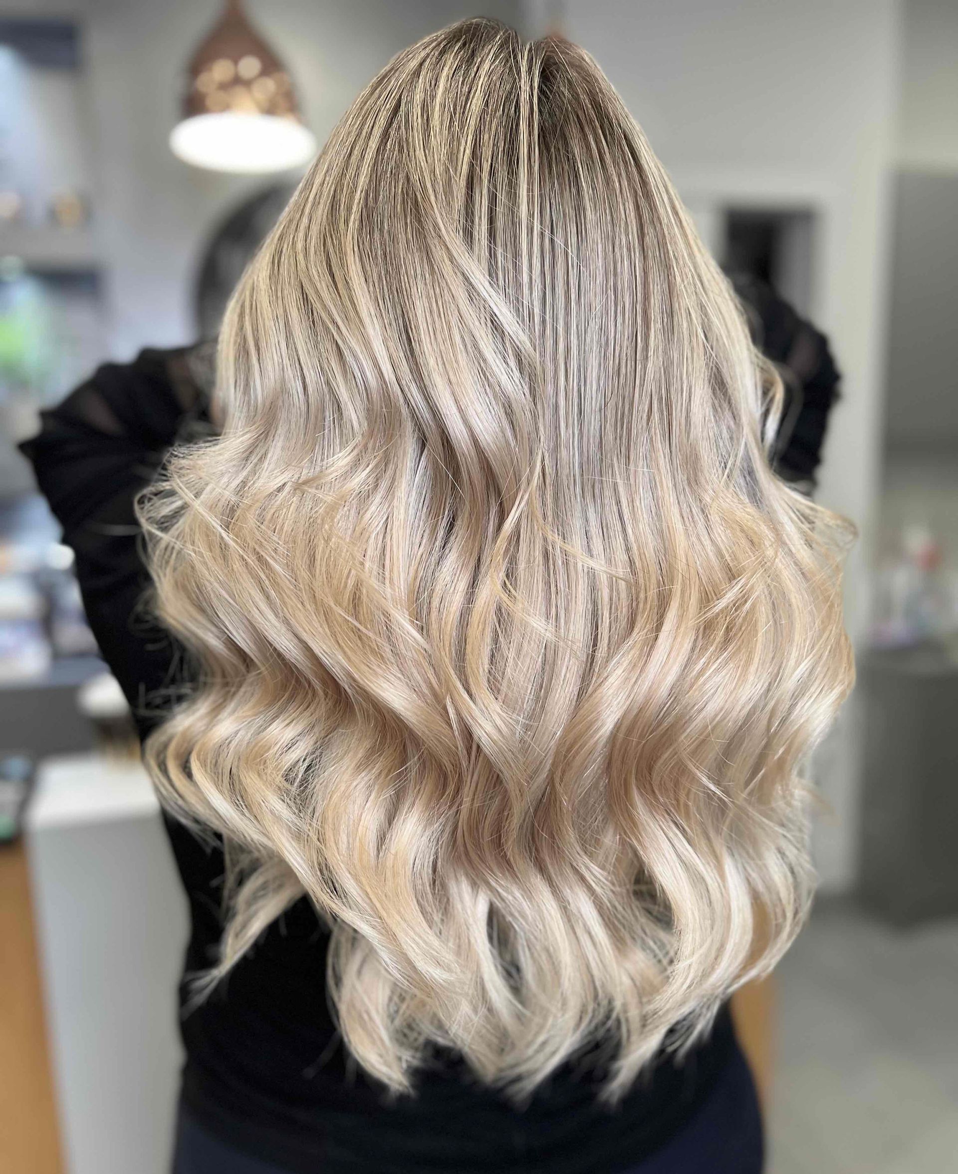 Wavy Platinum Blonde Hair With Dark Roots, Styled In Loose Curls Indoors — Oh So Blonde Hair Studio in Kawana, QLD