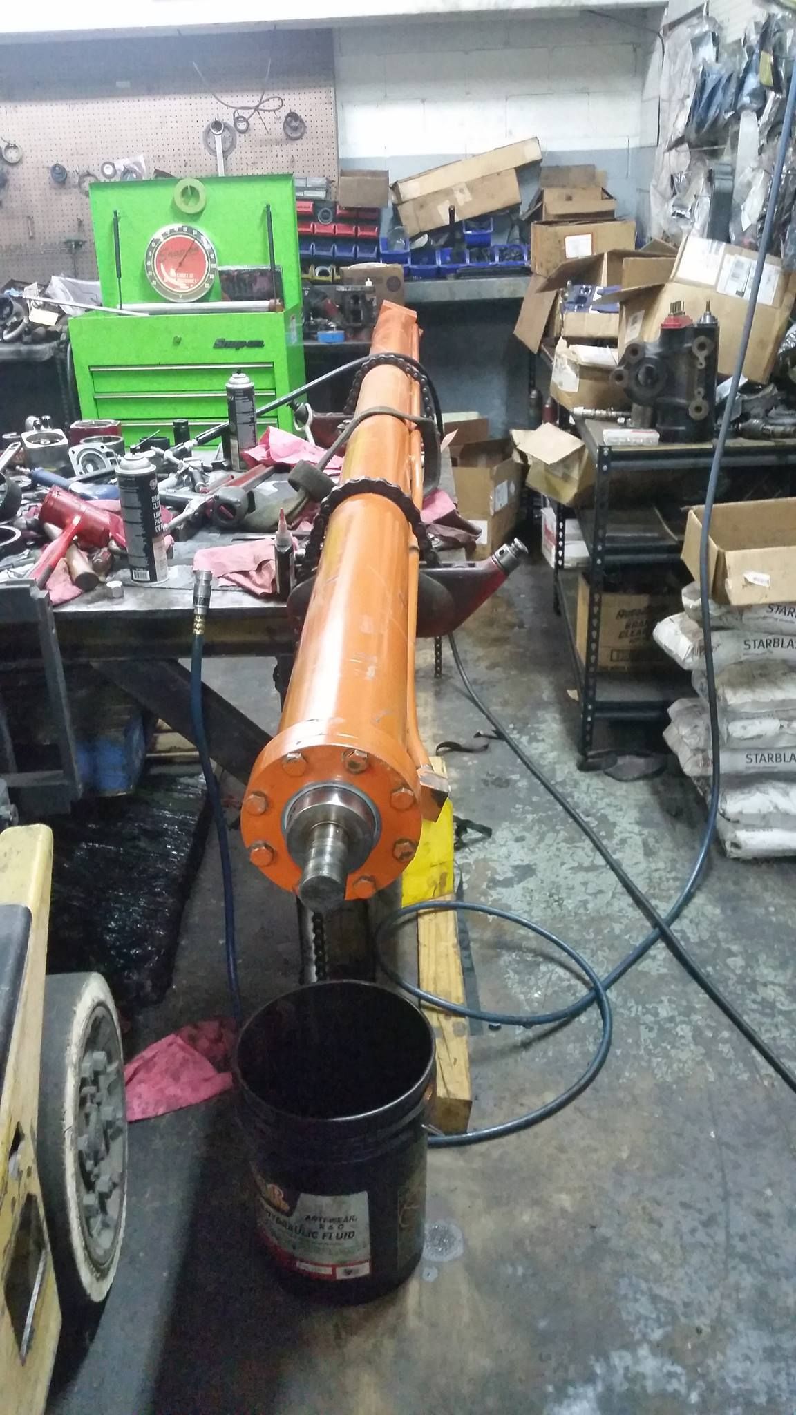 A Large Orange Pipe Is Sitting In A Garage Next To A Black Bucket — Lake City, GA — A-1 Hydraulics