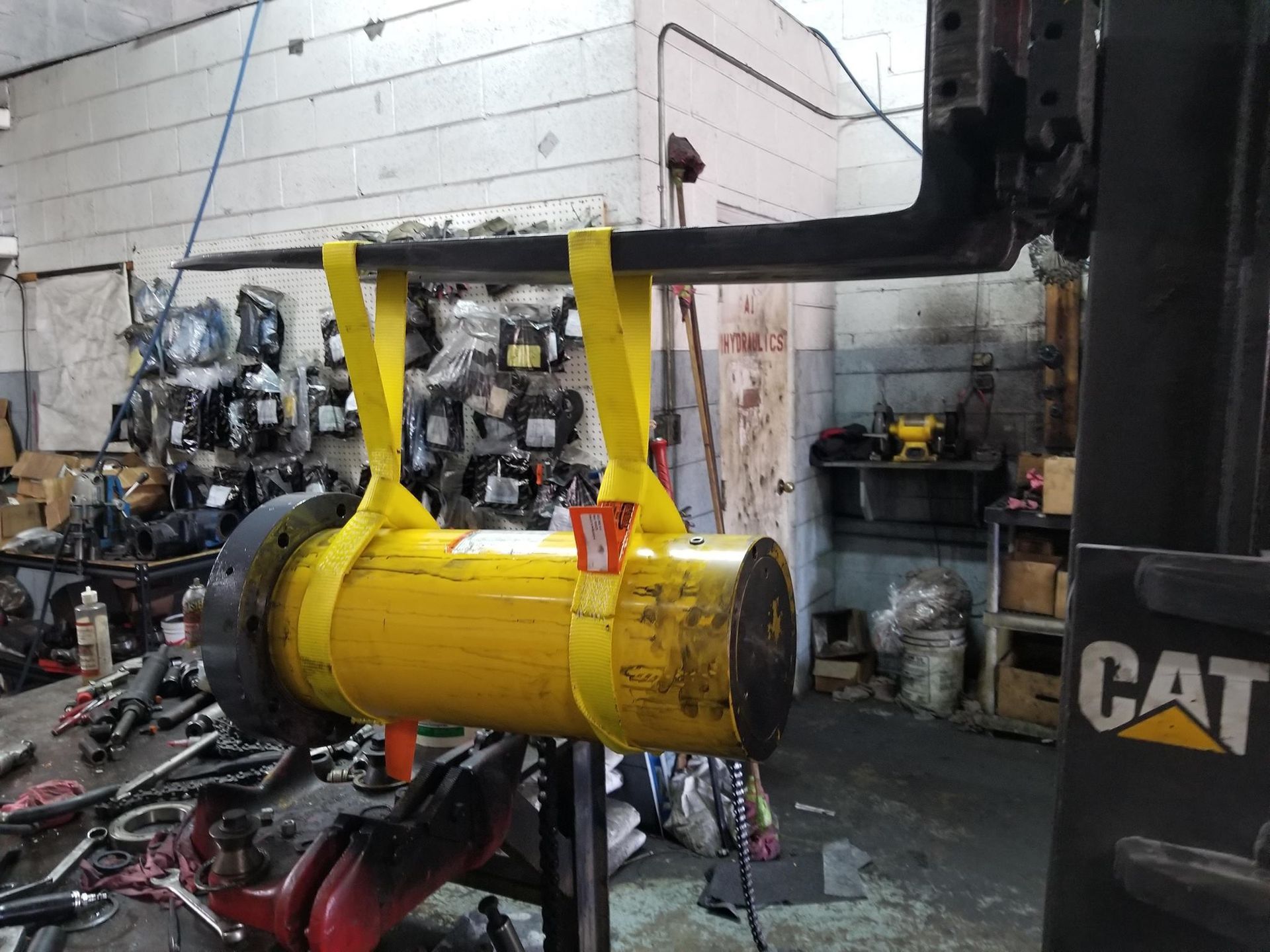 A Yellow Cylinder Is Being Lifted By A Cat Forklift In A Garage — Lake City, GA — A-1 Hydraulics